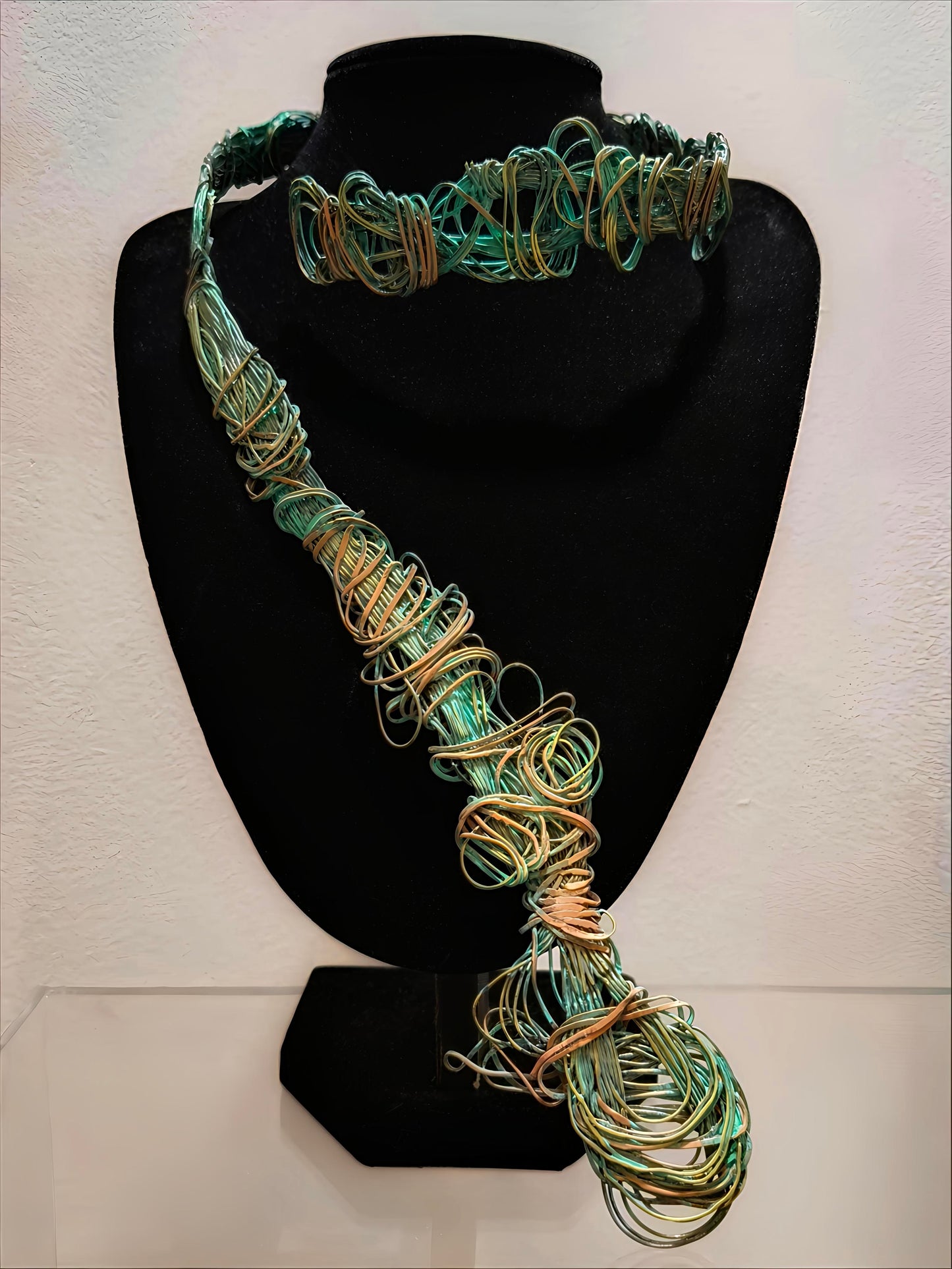 Detalle del collar de la colección Redes, elaborado con cobre y bronce. La imagen muestra el intrincado tejido metálico y las tonalidades verdosas que evocan las redes de pesca y las texturas del fondo marino, resaltando la destreza artística y técnica del diseño.